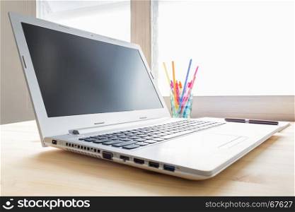 Laptop and notebook and pen and glass on wood table in old office with soft evening light