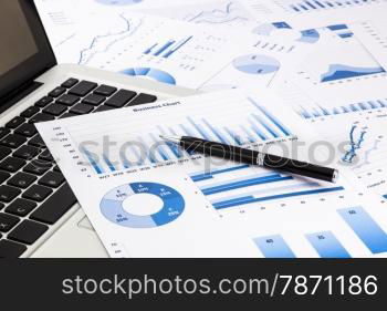 laptop and pen with blue business charts, graphs, statistic and documents background for education and business concepts