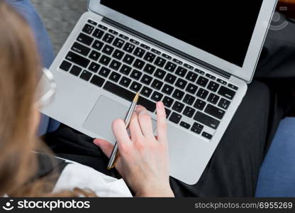 laptop, behind which works businesswoman top view closeup