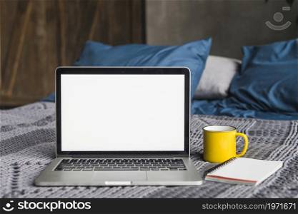 laptop blank white screen near cup spiral notepad bed. High resolution photo. laptop blank white screen near cup spiral notepad bed. High quality photo