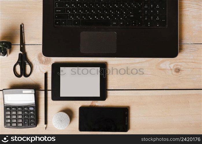laptop calculator pencil scissor cell phone wireless speaker ebook reader wooden desk