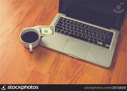 Laptop Coffee Mug and money on a wooden table.vintage effect style pictures