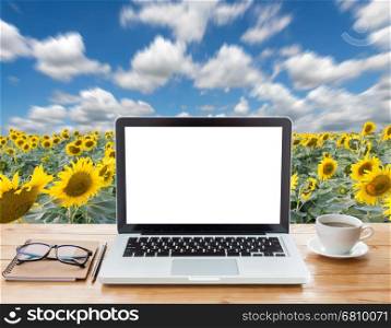 laptop computer and coffee on sunflower field background