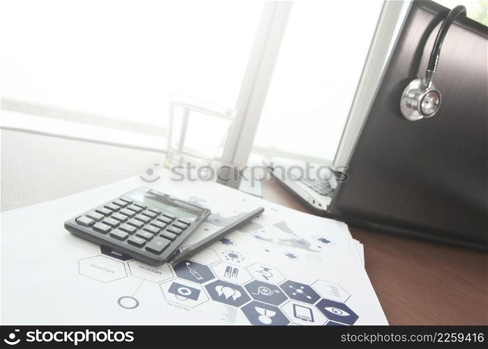 laptop computer and stethoscope and calculater in medical workspace office and medical network media diagram as concept