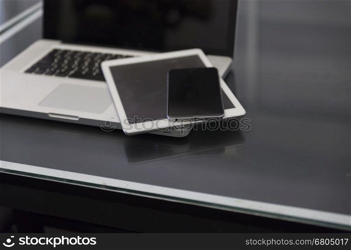laptop computer, digital tablet and mobile phone on black table for working concept