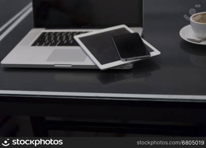 laptop computer, digital tablet and mobile phone on black table for working concept