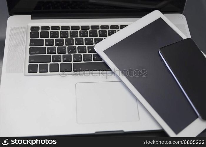 laptop computer, digital tablet and mobile phone on black table for working concept