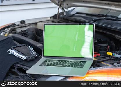 Laptop computer on car hood for engine diagnostic. Car garage repair service concept.