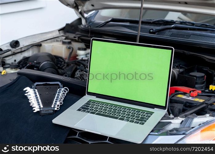 Laptop computer on car hood for engine diagnostic. Car garage repair service concept.