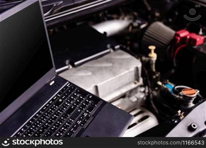 Laptop computer on car mechanic engine for service at workshop