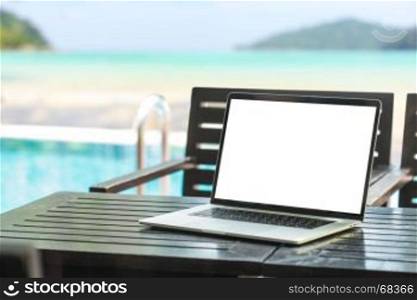 laptop computer showing blank screen on table beauty beach background