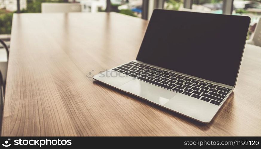 Laptop computer with opened lid on table in office workspace.