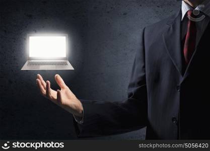 Laptop in hand. Close up of businessman holding laptop in palm