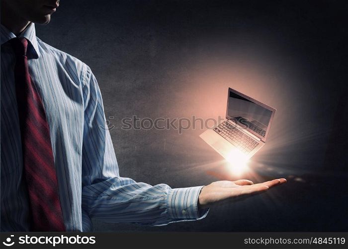 Laptop in hand. Human hand holding in palm glowing laptop