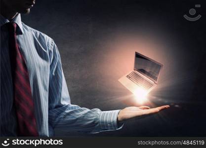 Laptop in hand. Human hand holding in palm glowing laptop