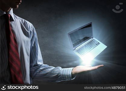 Laptop in hand. Human hand holding in palm glowing laptop