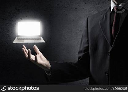 Laptop in male hand. Hand of businessman holding glowing laptop in palm