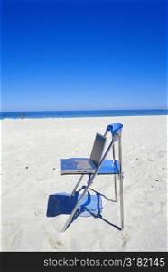 Laptop lying on a chair on the beach