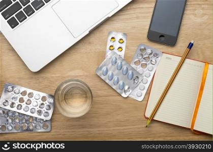 Laptop, mobile phone and pills and glass of water