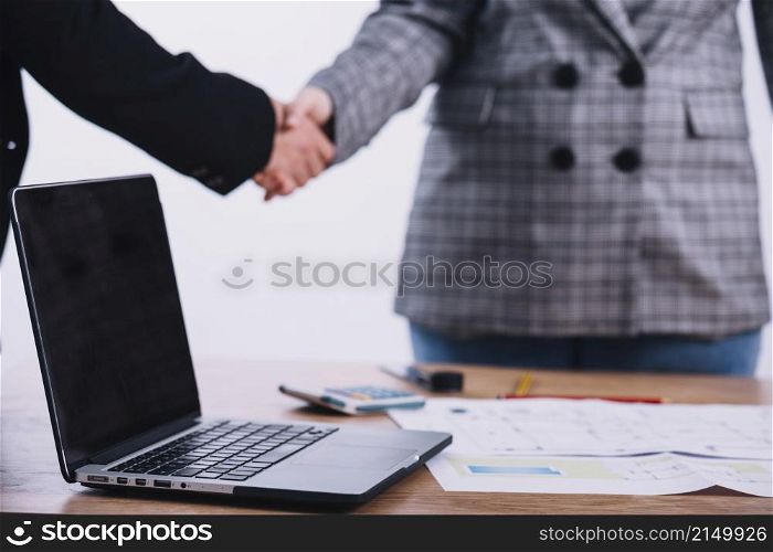 laptop near people shaking hands