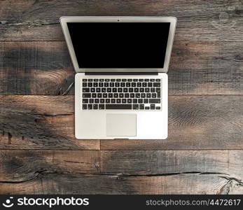 Laptop notebook with black screen on wooden table desk. Office workspace background. German lettering