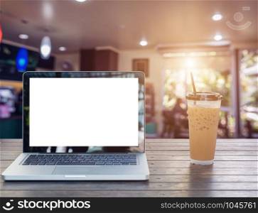 Laptop Notebook with iced coffee cup on wooden table in coffee shop