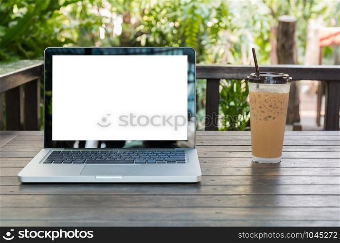 Laptop Notebook with iced coffee cup on wooden table in coffee shop and garden background