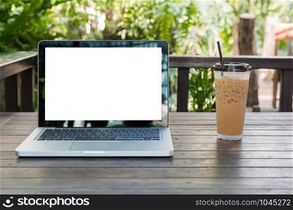 Laptop Notebook with iced coffee cup on wooden table in coffee shop and garden background