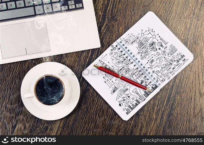 Laptop notepad with sketches and cup of coffe on table. Work place