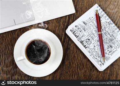 Laptop notepad with sketches and cup of coffe on table. Work place