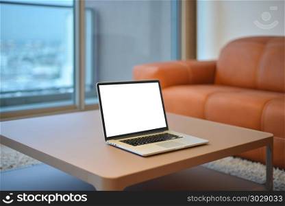 Laptop on table in modern living room with blank screen