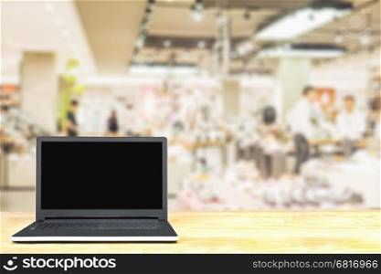 Laptop on wooden table over blurred superstore background