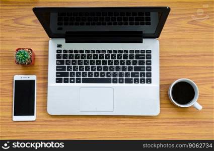 laptop on wooden table with coffee cup, phone and cactus on top view