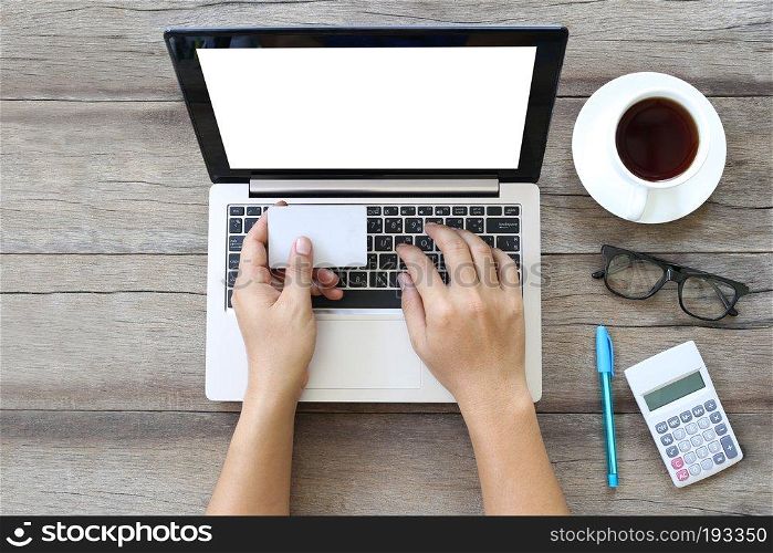 Laptop or notebook on wooden work table and white card in hand of business man,Business concept and a credit card.