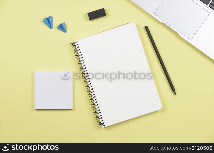 laptop pencil spiral notebook adhesive notepad airplane eraser yellow background