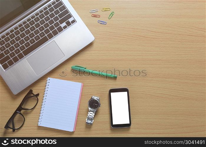Laptop placed near a empty notebook and blank smartphone on a br. Laptop placed near a empty notebook and blank smartphone on a brown wooden floor and have copy space for design in your work.