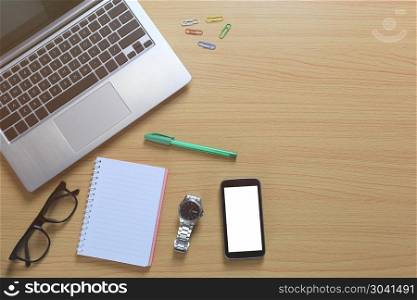 Laptop placed near a empty notebook and blank smartphone on a br. Laptop placed near a empty notebook and blank smartphone on a brown wooden floor and have copy space for design in your work.
