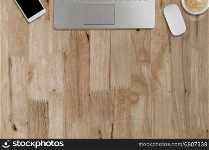 laptop, smartphone, mouse, coffee cup on wooden desk - top view with copy space