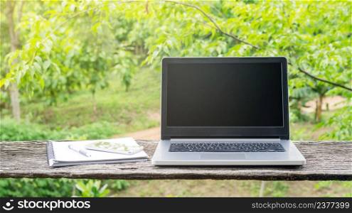 Laptop, smartphone, pen, and book on a wooden table.