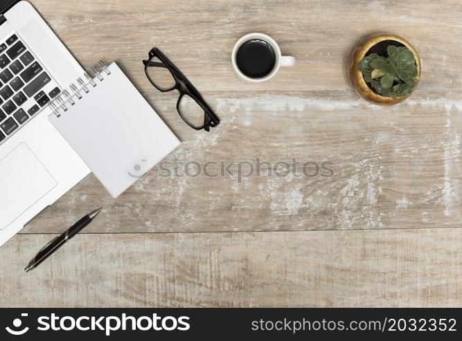 laptop spiral notepad eye glasses black tea plant wooden table