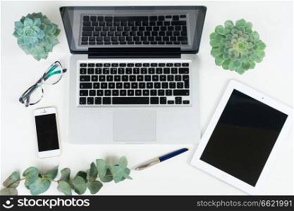 Laptop, tablet and phone with green plants mock up flat lay styled scene, top view, copy space on black screen background. Offise desktop scene