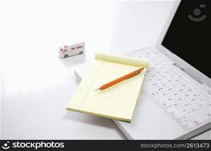 Laptop with a note pad and pen on top