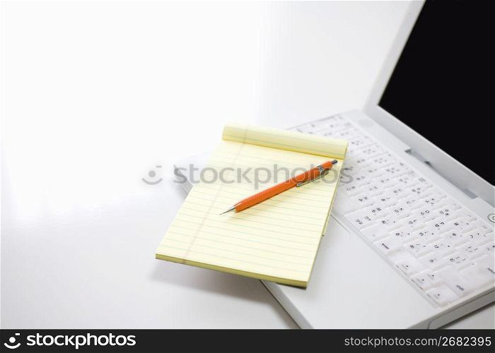 Laptop with a note pad and pen on top
