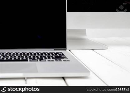 Laptop with black screen on white wooden table by white background