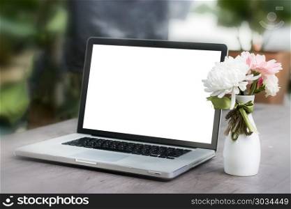 Laptop with blank screen on table and flower
