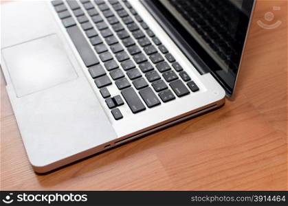 Laptop with blank screen on wood table.