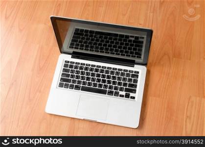 Laptop with blank screen on wood table.