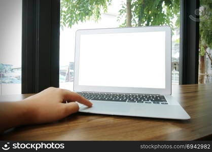 Laptop with blank screen on wooden table in front of coffeeshop cafe - technology concept.