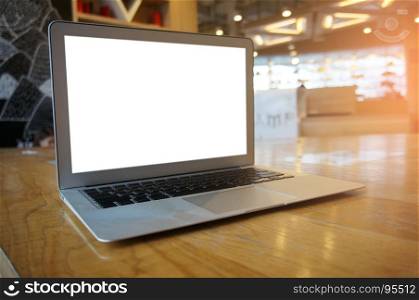 Laptop with blank screen on wooden table in front of coffeeshop cafe - technology concept.