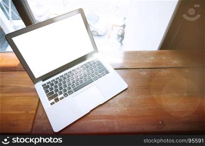 Laptop with blank screen on wooden table in front of office window